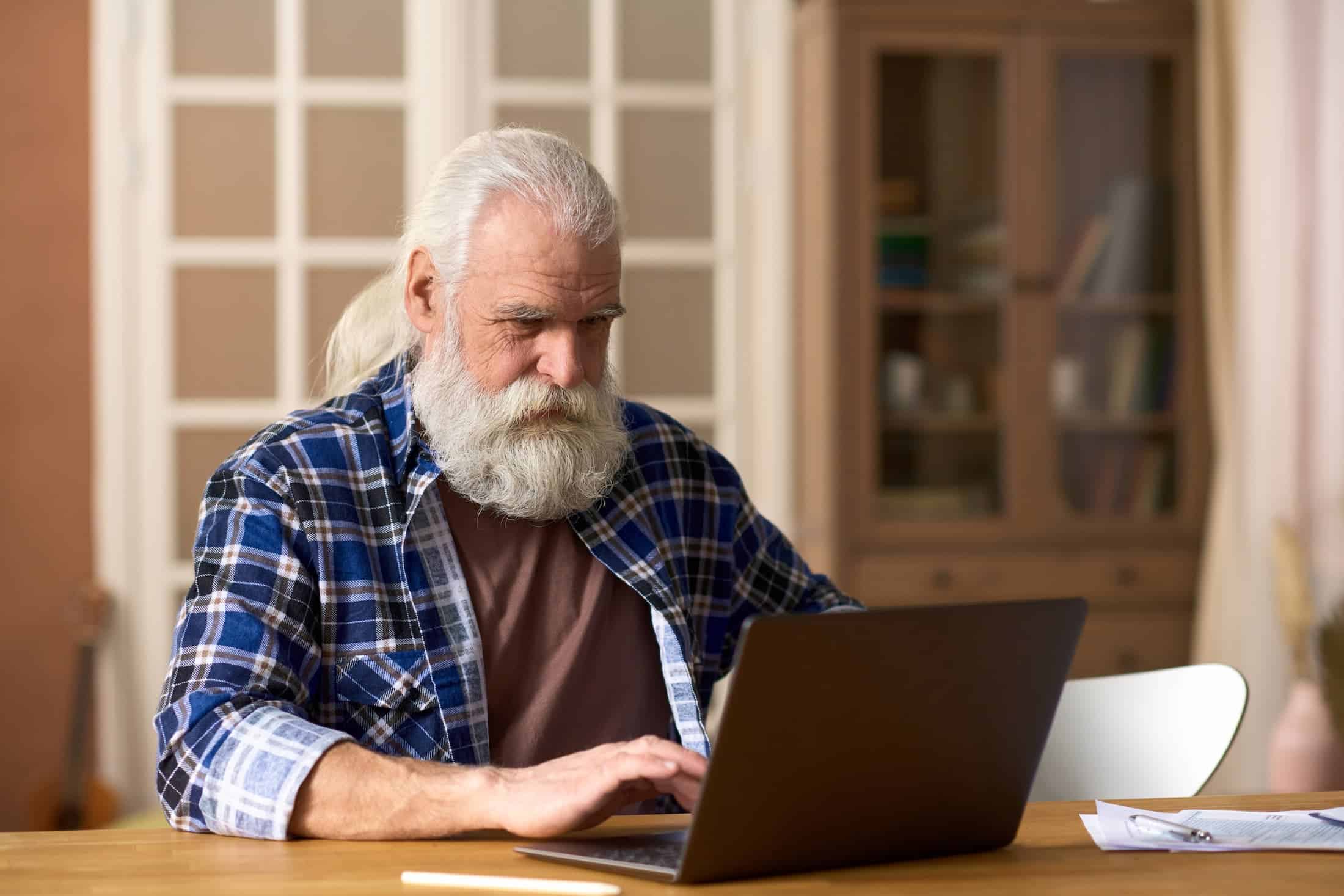 Senior man with white beard using laptop